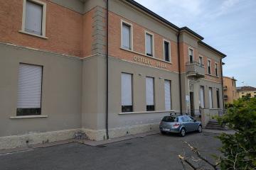 The image shows the exterior of a two-story building with brick and stucco facade, featuring signage that reads "OSTELLO DELLA GIOVENTU" above the entrance, with a silver car parked in front and greenery to the right.