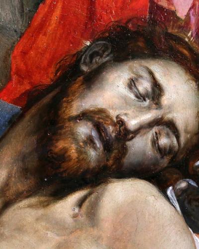 A close-up detail of a Renaissance oil painting depicting the dead body of Christ (Lamentation/Compianto) with a halo, red drapery, and a blue garment, showing visible craquelure and paint texture.