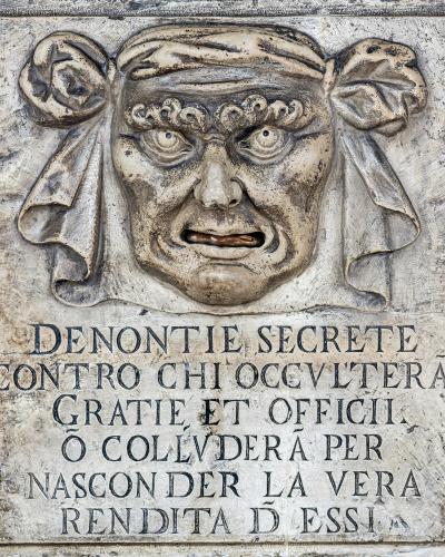 A stone relief sculpture of a grotesque face with a mouthpiece (the "Bocca di Leone" or "Lion's Mouth) and an inscription below in Italian reading "DENONTIE SECRETE..." (Secret Denunciations...).