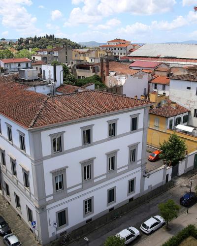 An elevated view of a large, white, multi-story building with a terracotta-tiled roof situated at a street corner, with a construction crane and scaffolding visible on an adjacent structure to the right.