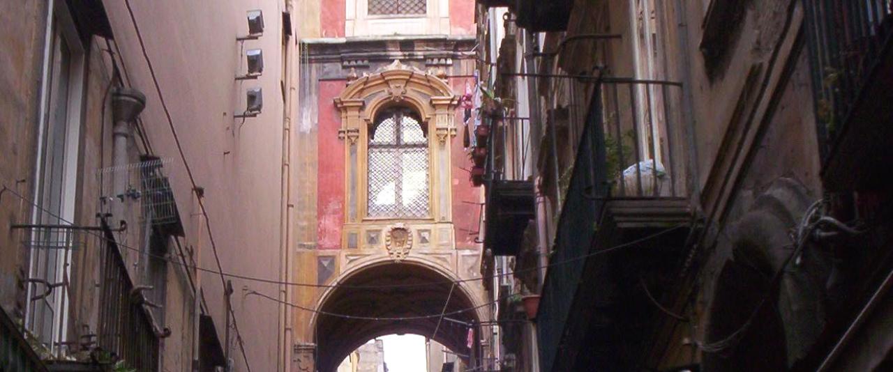 Via San Gregorio Armeno in Naples with workshop displays and the convent bell tower arching over the lane