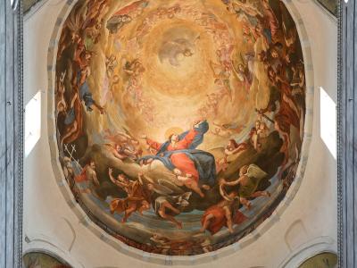 The image shows a large, circular ceiling fresco depicting the Assumption of Mary surrounded by angels and saints, located inside a church with architectural features like arches, windows, and a staircase leading up to the dome; the artwork is sig