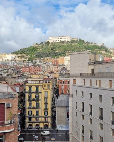 A view of the Naples cityscape looking up toward the Vomero hill, where the large white building complex of the Certosa di San Martino is visible at the summit.