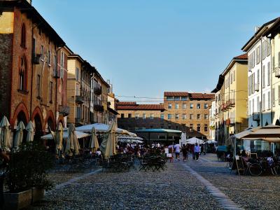 The image shows Piazza della Vittoria in Brescia, Italy, featuring the prominent Torre del Comune (or Torre dell'Orologio) and the Palazzo delle Poste e Telegrafi with its distinctive striped facade and inscribed text "POSTE E TELEGRAFI".