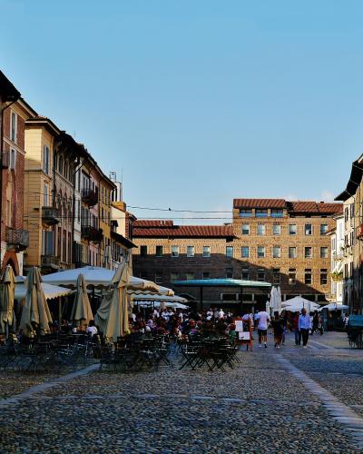 The image shows Piazza della Vittoria in Brescia, Italy, featuring the prominent Torre del Comune (or Torre dell'Orologio) and the Palazzo delle Poste e Telegrafi with its distinctive striped facade and inscribed text "POSTE E TELEGRAFI".