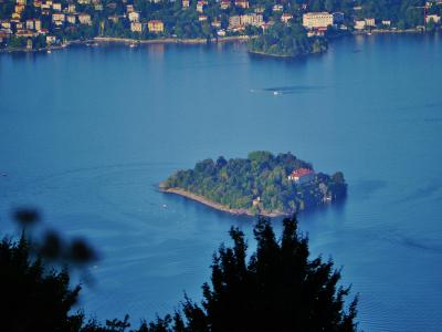 A high-angle view of Lake Maggiore showing the island of Isola Madre in the foreground and the town of Stresa with its waterfront buildings on the far shore.
