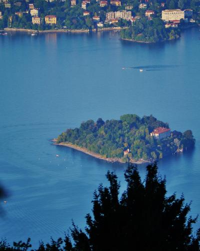 A high-angle view of Lake Maggiore showing the island of Isola Madre in the foreground and the town of Stresa with its waterfront buildings on the far shore.