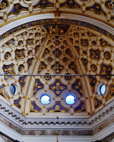 The image shows an ornate, gilded ceiling vault with blue and gold decorative patterns, circular windows, and hanging chains, identified by the filename as the choir vault of the Santuario di Santa Maria dei Miracoli presso San Celso in Milan.