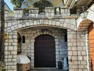 The image shows the stone entrance archway of a building with a large arched sign reading "PRESEPIO" in gold letters, a dark wooden gate, and a paved courtyard with a scalloped tile pattern.