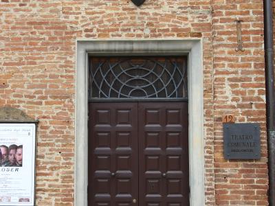 The image shows the entrance to a brick building with a plaque reading "TEATRO COMUNALE DEGLI OSCURI" and a poster for "Accademia degli Oscuri," located at number 12.