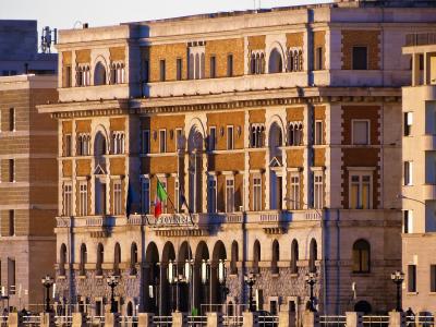 A large, ornate historic building with arched windows and a stone facade, featuring Italian and regional flags and the word "PROVINCIA" inscribed above the entrance.