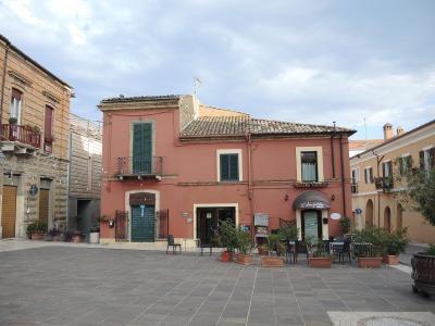 The image shows a paved public square in front of a salmon-pink building with green shutters and an awning labeled "La Langhetto," identified by the filename as Piazza Ducale in Giulianova, Italy.