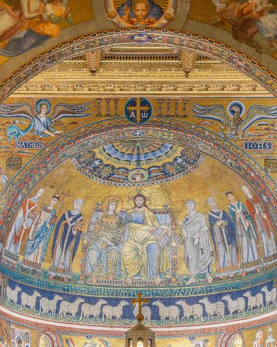 The image shows the interior apse mosaic of a church, featuring Christ enthroned with saints and angels, flanked by figures labeled "MATHEUS" and "IOHS," with Latin inscriptions and a golden background typical of Byzantine-style religious art.