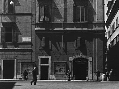A black-and-white photograph of a street corner in Rome showing a building facade with a sign reading "Galleria ai Quattro Venti" above an arched entrance, and a street sign for "Largo di Torre Argentina" on the adjacent building.