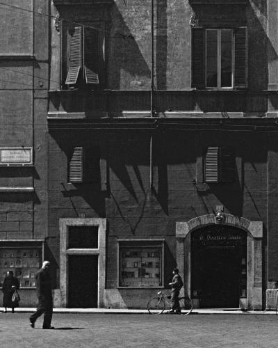 A black-and-white photograph of a street corner in Rome showing a building facade with a sign reading "Galleria ai Quattro Venti" above an arched entrance, and a street sign for "Largo di Torre Argentina" on the adjacent building.