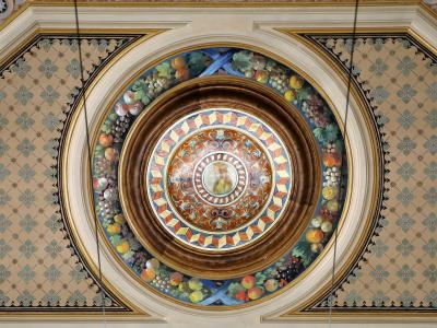 The image shows an ornate, painted ceiling medallion featuring a central portrait surrounded by fruit garlands and geometric patterns, with decorative borders and hanging wires visible.