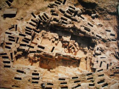 An aerial view of the Tuvixeddu necropolis in Cagliari, Sardinia, showing the distinctive rock-cut tombs and burial structures carved into the limestone hillside.