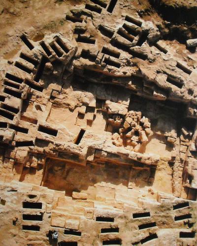 An aerial view of the Tuvixeddu necropolis in Cagliari, Sardinia, showing the distinctive rock-cut tombs and burial structures carved into the limestone hillside.