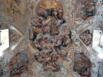 The image shows an ornate Baroque ceiling fresco with elaborate stucco work, painted scenes of religious figures and cherubs, and architectural illusionism typical of 18th-century Sicilian church interiors.