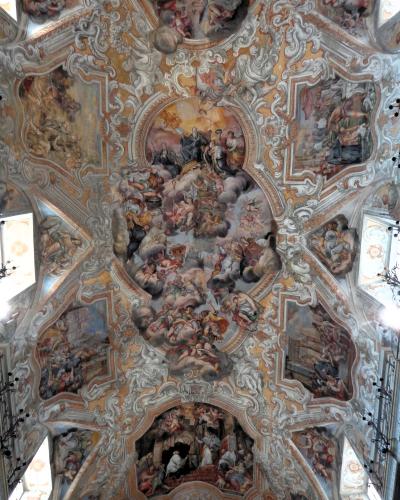 The image shows an ornate Baroque ceiling fresco with elaborate stucco work, painted scenes of religious figures and cherubs, and architectural illusionism typical of 18th-century Sicilian church interiors.