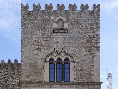 A stone medieval tower facade featuring a triple-arched Gothic window, a small balcony above it, crenellations at the top, and a Latin inscription frieze reading "DEVVM DILIGERE PRVDENTIA EST ESVM IMITARI IVSTICIA".