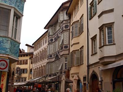 The image shows Piazza delle Erbe in Verona, Italy, featuring the Palazzo Maffei with its distinctive statues on the roofline, the Torre dei Lamberti to the left, and a central column with a statue (likely the Lion of Saint Mark) in the foreground