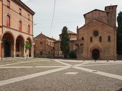 A view of Piazza Santo Stefano in Bologna, Italy, showing the distinctive brick architecture of the seven churches complex, including the Church of San Stefano Maggiore on the right and the arcaded buildings of the seminary on the left, with a cob