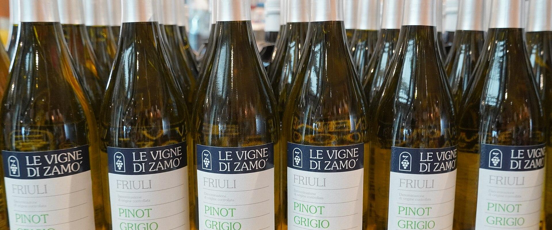 Rows of wine bottles labeled "LE VIGNE DI ZAMO", "FRIULI", and "PINOT GRIGIO" arranged on a wooden surface in what appears to be a retail or tasting room setting.