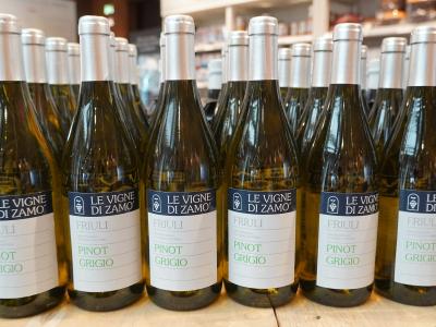 Rows of wine bottles labeled "LE VIGNE DI ZAMO", "FRIULI", and "PINOT GRIGIO" arranged on a wooden surface in what appears to be a retail or tasting room setting.