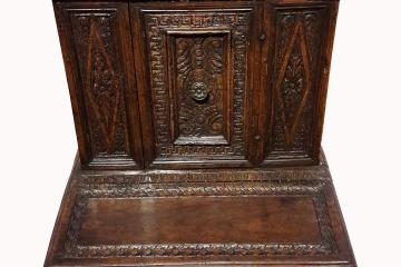 A dark wooden Renaissance-style prayer desk (or prie-dieu) with carved panels, a central door with a metal knob, and an attached kneeler, photographed against a plain white background.