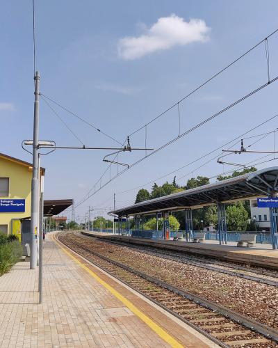 The image shows the platform and tracks of the Bologna Borgo Panigale railway station, identifiable by the blue station signs reading "Bologna Borgo Panigale" on both sides of the tracks.