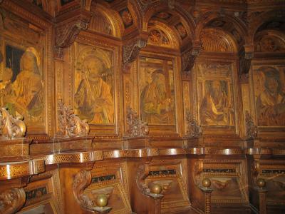 The image shows an ornate, gilded wooden choir stall (coro) featuring painted panels of saints and intricate marquetry, with identifying text "Coro rinascimentale, Certosa di Pavia, Lombardia" in the filename.