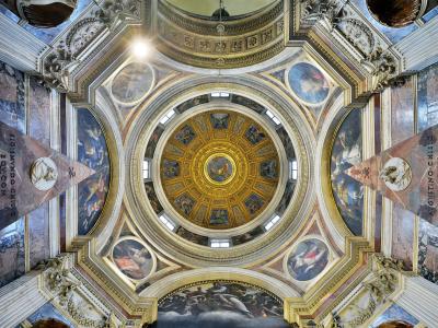 A low-angle interior view of an ornate, gilded dome ceiling with frescoes, marble columns, and inscriptions on the piers, identified by the filename as the Cappella Chigi in Santa Maria del Popolo, Rome.