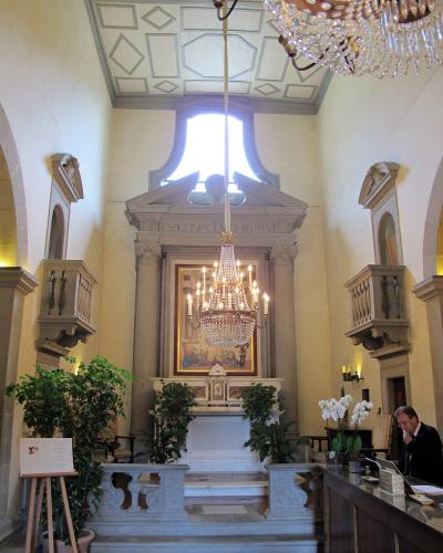 The image shows the interior of a chapel featuring a marble altar, a large painting, a crystal chandelier, and an inscription reading "RESPICE IN FACEM CHRISTI" on the architrave.