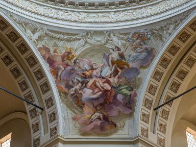 The image shows the interior ceiling of a church dome featuring a Baroque-style fresco of religious figures surrounded by stucco decorations and architectural moldings.