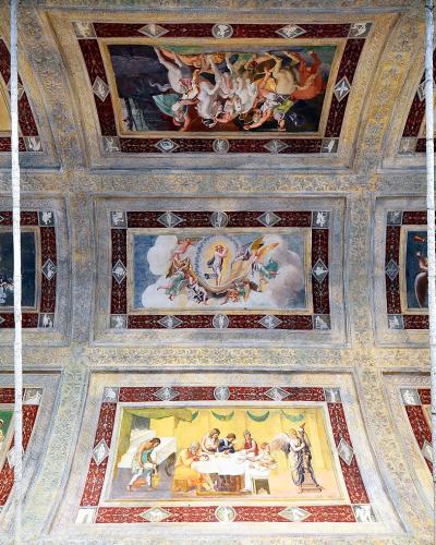 A vaulted ceiling frescoed with multiple rectangular panels depicting mythological and allegorical scenes, framed by decorative borders and architectural elements, with vertical white cables or ropes running down the center.