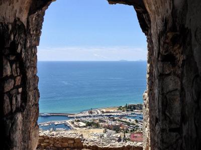 A view through a stone archway looking down at the harbor and coastline of Terracina, Italy.