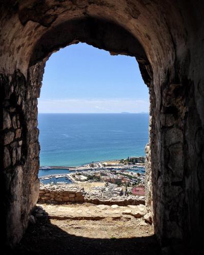 A view through a stone archway looking down at the harbor and coastline of Terracina, Italy.