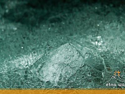 A close-up photograph of textured ice formations with a logo in the bottom right corner reading "etna walk" accompanied by a stylized mountain and sun graphic.