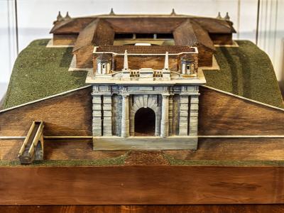 A detailed scale model of a fortified star-shaped city with a prominent arched gate (Porta Udine) and surrounding ramparts, displayed indoors on a wooden base.
